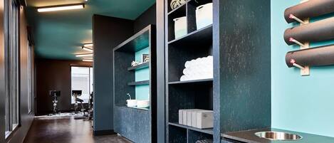 Un baño moderno con una pared verde oscuro, un espejo grande y repisas con artículos de aseo.