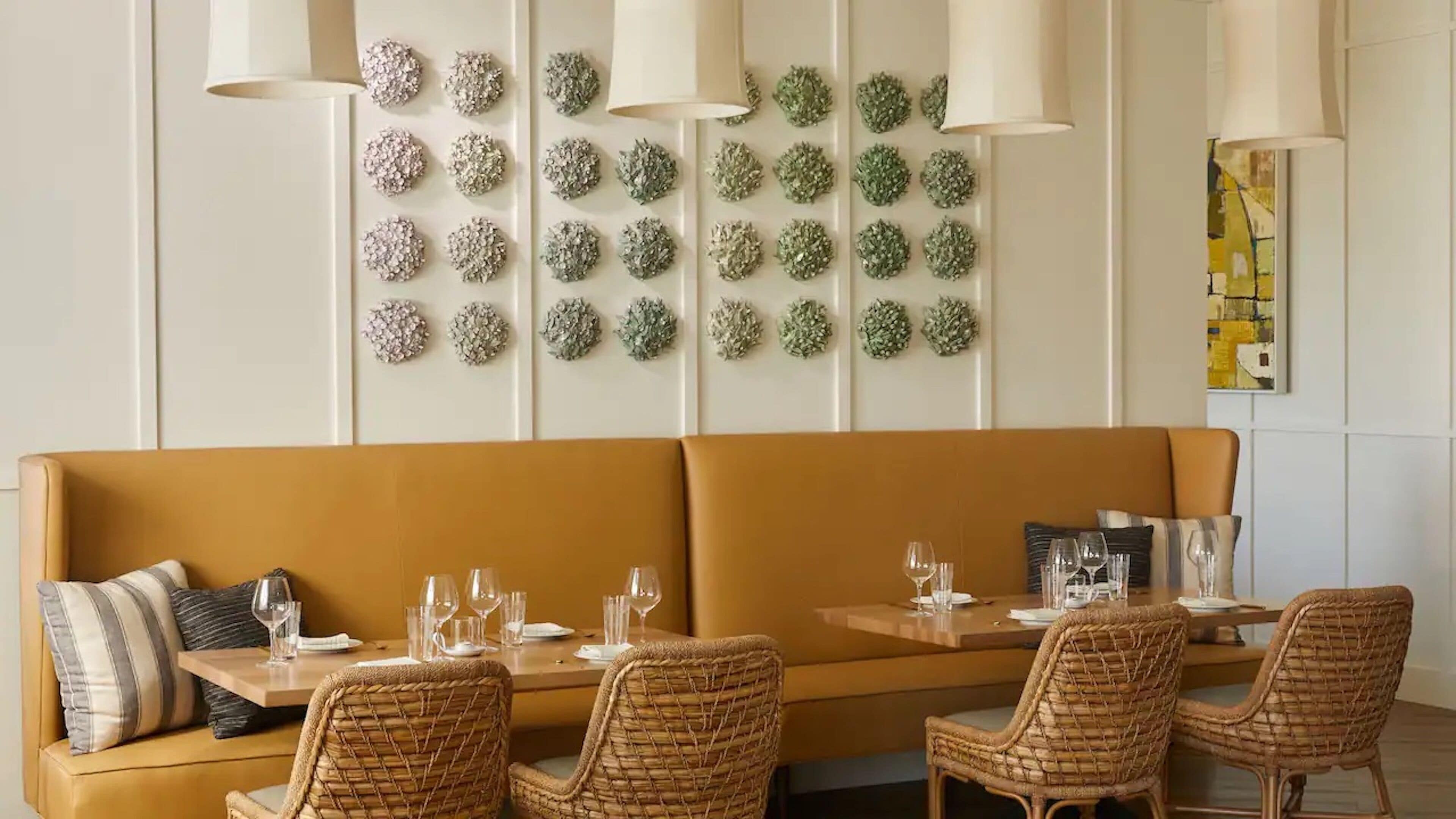 A dining area with a brown sofa, wicker chairs, and a table set with glasses and plates.