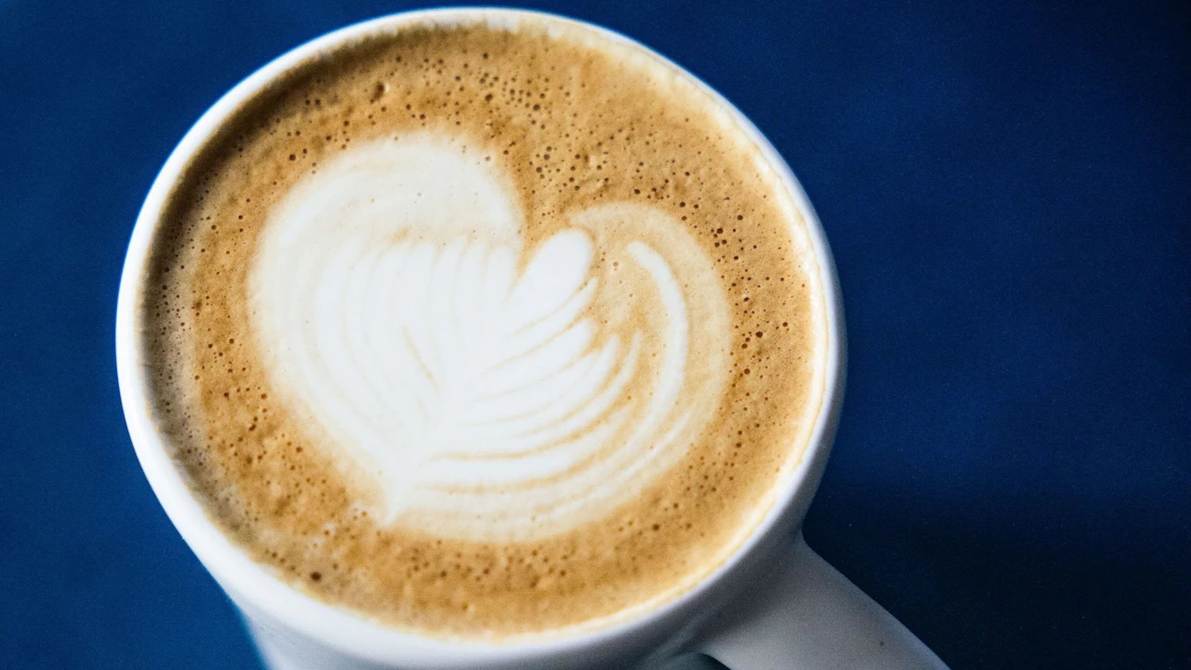 A cup of coffee with latte art in the shape of a heart.