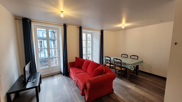 Un salon avec un canapé rouge, une table à manger avec des chaises et un meuble pour la télévision.