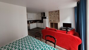 Une pièce de taille modeste comprenant un lit, un canapé rouge, une table à manger et un coin cuisine à l’arrière-plan.