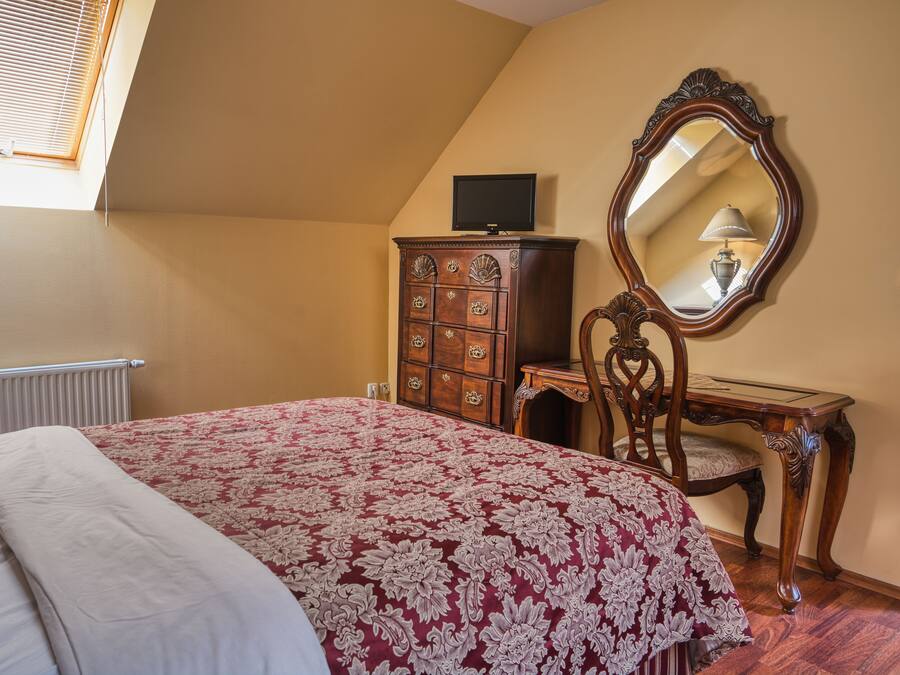 Un dormitorio con cama, cómoda, silla y espejo.