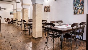 Een ruime eetruimte met hoge plafonds, stenen zuilen en modern meubilair.