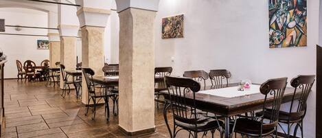 A spacious dining area with high ceilings, stone columns, and modern furniture.