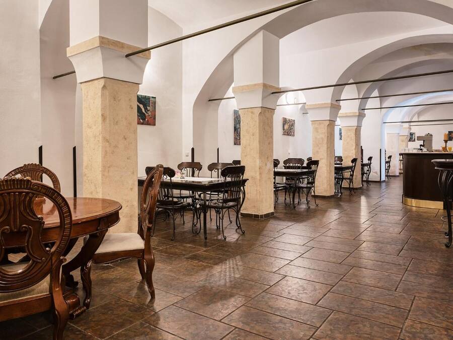 Un comedor espacioso con techos altos y arcos, que cuenta con varias mesas y sillas.