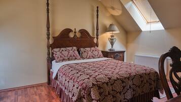 A bedroom with a four-poster bed, a nightstand with a lamp, and a radiator.