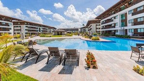 Een modern hotel met een groot zwembad, terras en een verzorgde tuin.