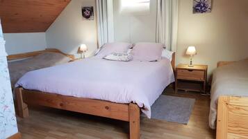 A cozy bedroom with a wooden bed, two bedside tables with lamps, a small wall decoration, and a window with curtains.