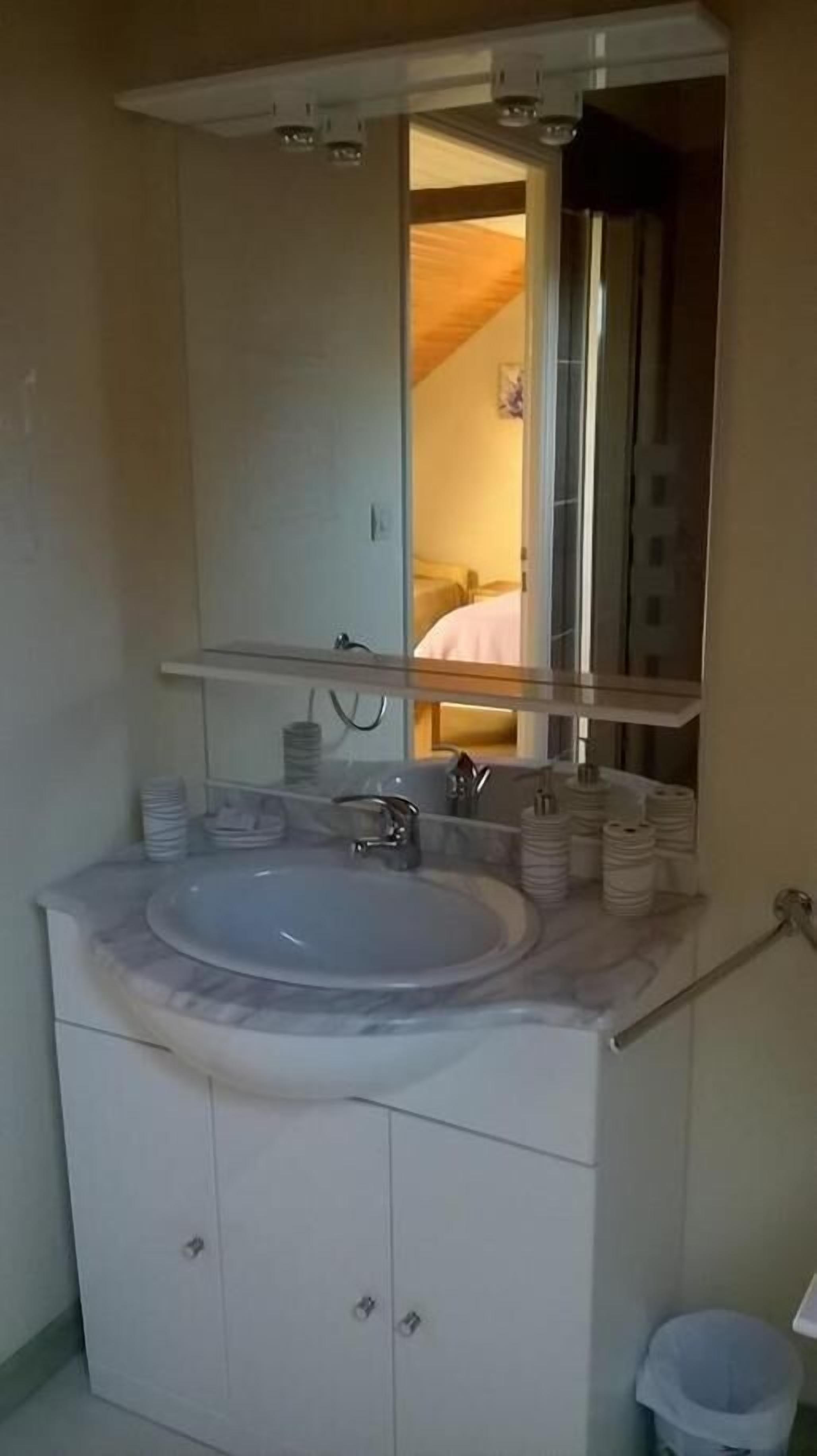 A bathroom with a large sink, mirror, and cabinets.