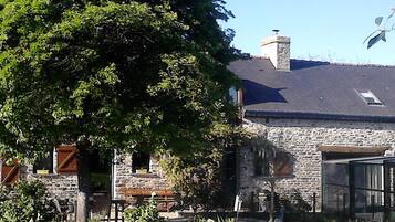 A stone building with a sloped roof, a chimney, and a wooden bench in the foreground.