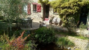 A stone house with a small garden, a pond, and outdoor furniture. - La P'tit' Fugue (La Bouexiere)