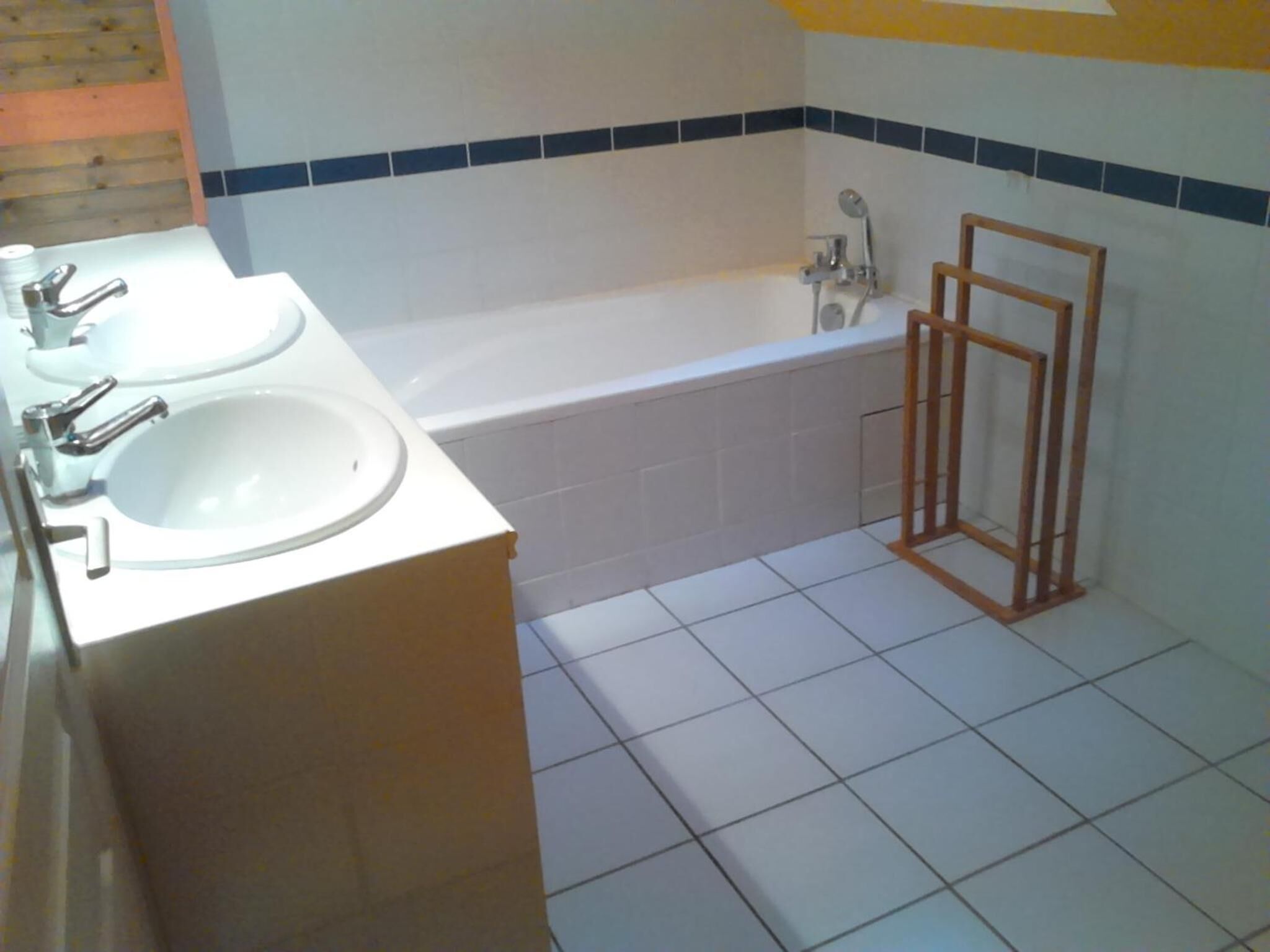 A bathroom with two sinks, a bathtub, and a wooden frame structure.