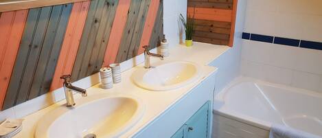 A bathroom with two sinks, a mirror, and a bathtub.