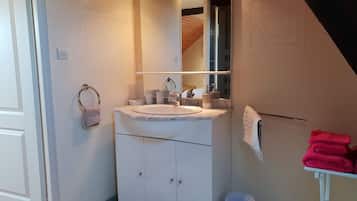 A bathroom with a sink, mirror, towel rack, and a small table with towels.