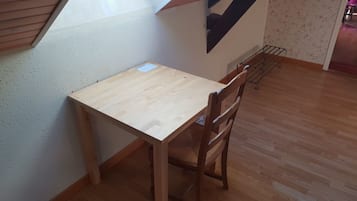 A small wooden table with a chair, a metal rack, and a patterned wall.