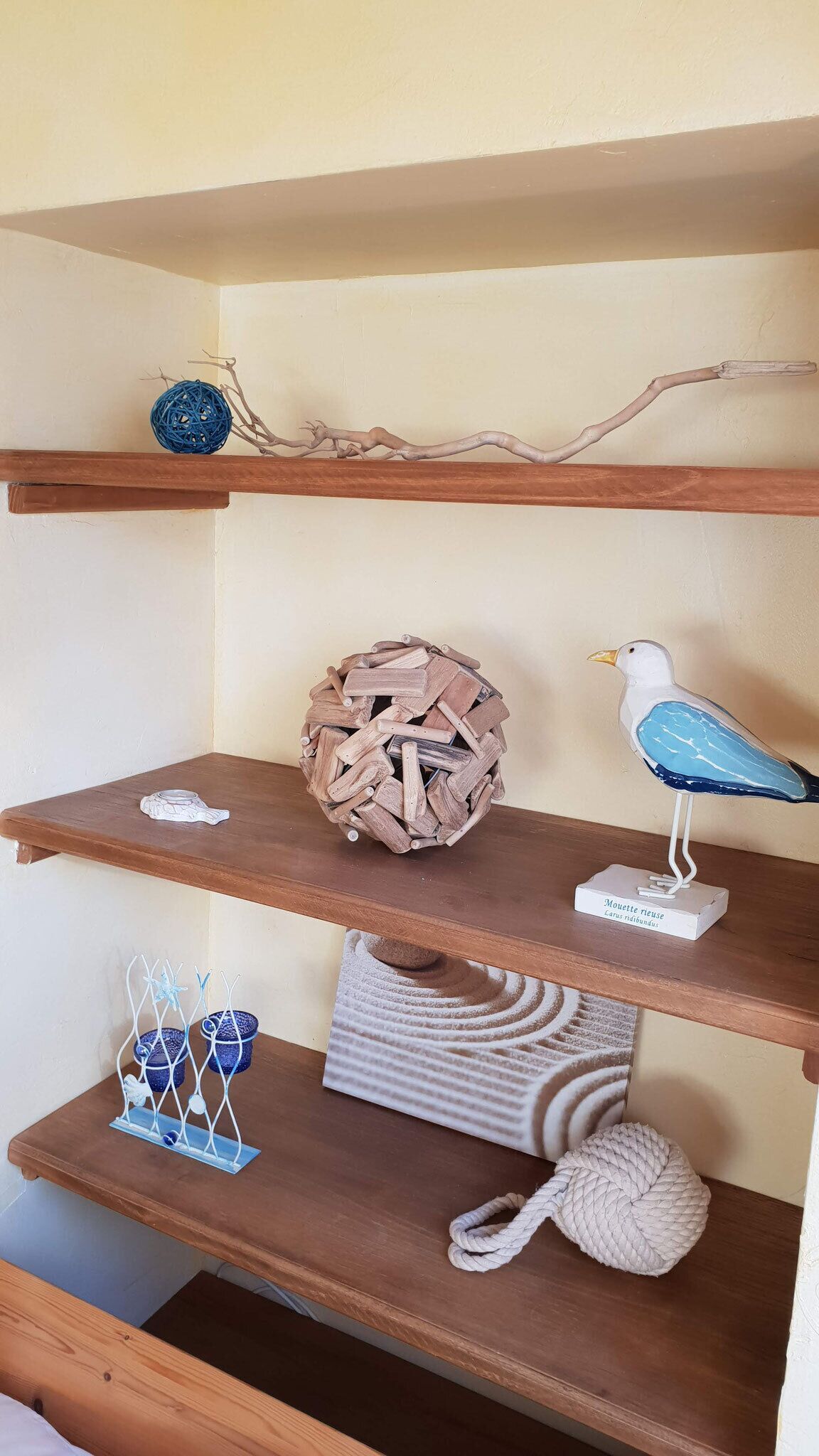A wooden shelf with decorative items including a bird sculpture, a woven ball, and a textured rug.