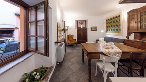 A dining area with a table, chairs, a radiator, a window, and a view of the outside.