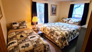 Un dormitorio con dos camas, una mesita de noche, una lámpara y una ventana con cortinas.