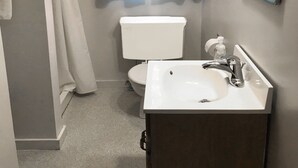 Baño con inodoro, lavabo y cortina de ducha.