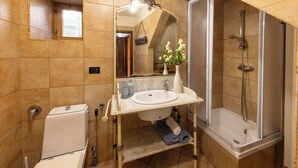 Une salle de bain comprenant des toilettes, un lavabo, un miroir, une douche et une petite fenêtre.