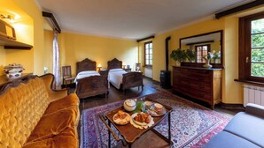 Une chambre confortable avec un grand lit, un canapé, une commode et une table à manger où le petit-déjeuner est servi.