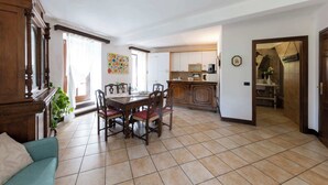 Un vaste espace de vie comprenant une table à manger, des chaises, un canapé et une cuisine en arrière-plan.