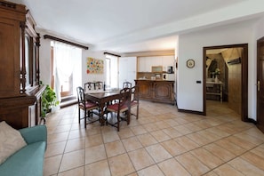 Un vaste espace de vie comprenant une table à manger, des chaises, un canapé et une cuisine en arrière-plan.