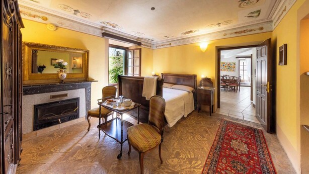 Une pièce avec une cheminée, un lit, une table avec des chaises et un grand miroir.
