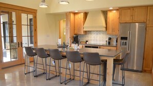 Una cocina moderna con armarios de madera, un refrigerador de acero inoxidable y una isla central con taburetes de bar.