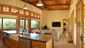 Una cocina amplia con una isla grande, armarios de madera y un techo alto con vigas a la vista.