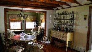 A dining area with a round table and chairs, a chandelier, and a decorative metal rack against the wall. - Charming cottage on the water with beautiful views (Lakeville)