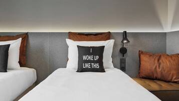 Ein Hotelzimmer mit zwei Betten, einem Nachttisch, einer Lampe und einer Wandleuchte.