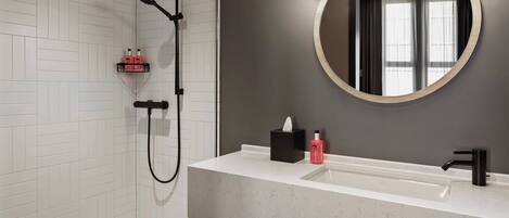 Un bagno moderno con doccia rivestita in piastrelle bianche, un ampio specchio e un lavandino bianco con rubinetto nero.