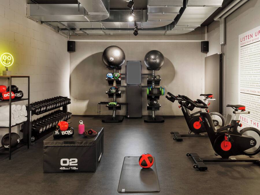 Ein Fitnessstudio mit Trainingsgeräten, einem Sandsack und einem neonfarbenen Schild mit einem Smiley.