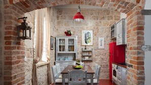 A rustic kitchen with exposed brick walls, a wooden dining table, and a red refrigerator. - Luxury Villa Lighthouse Beyond (Vis)