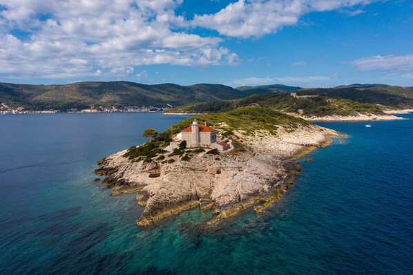 Une île isolée, avec un petit bâtiment en pierre, entourée d’eaux d’un bleu limpide et de montagnes lointaines.