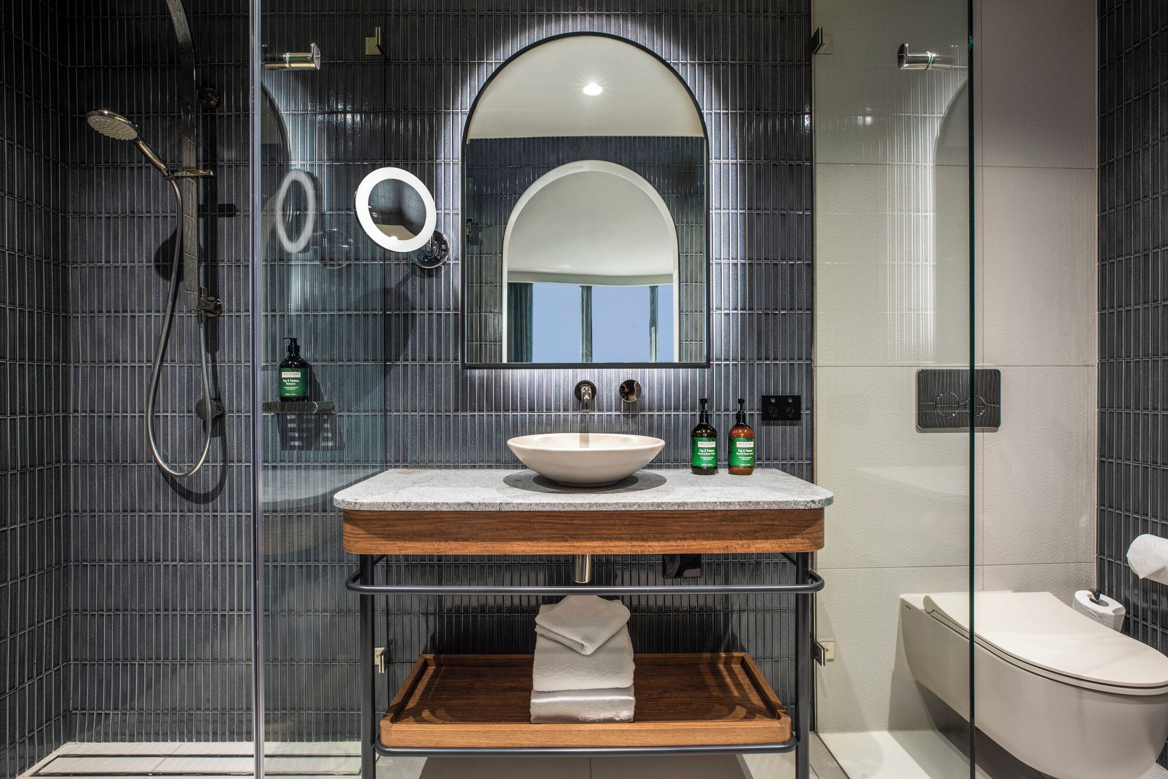 Un baño moderno con lavamanos independiente, un espejo grande y cabina de ducha con paredes de vidrio.