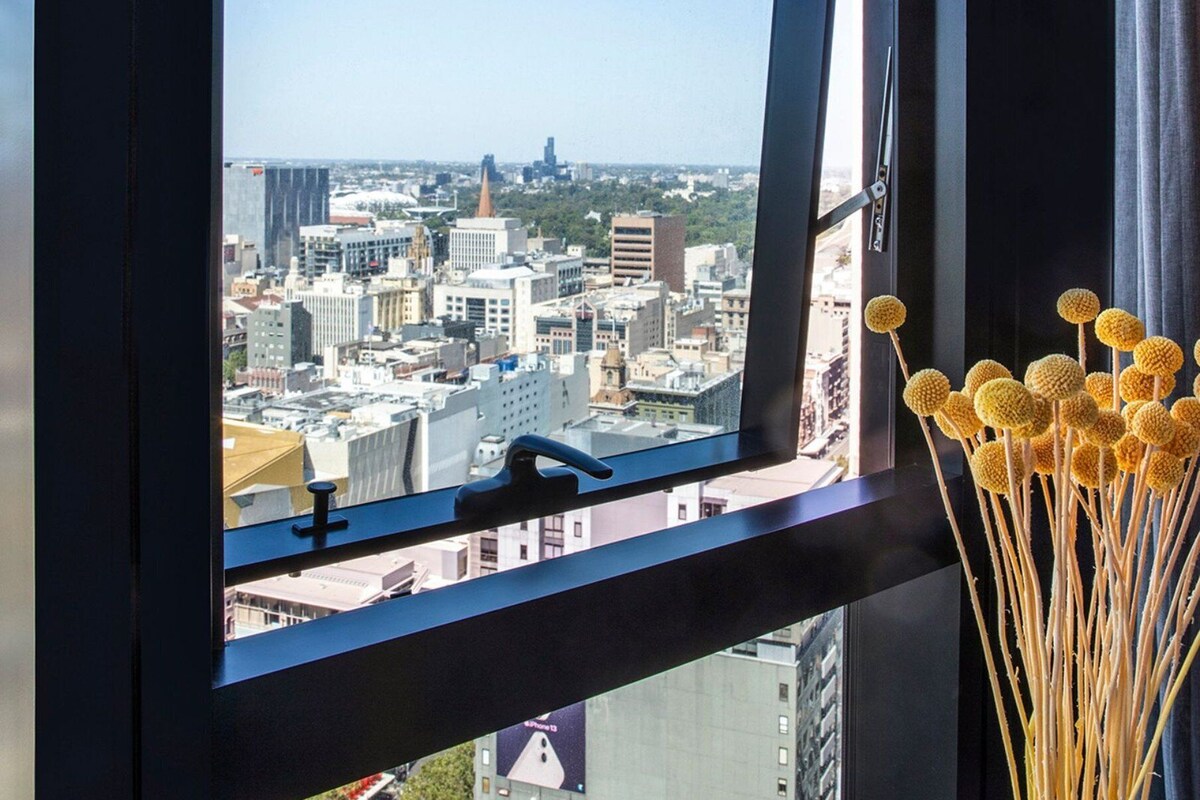 Vista desde una ventana que muestra un paisaje urbano, con edificios y la aguja de una iglesia.