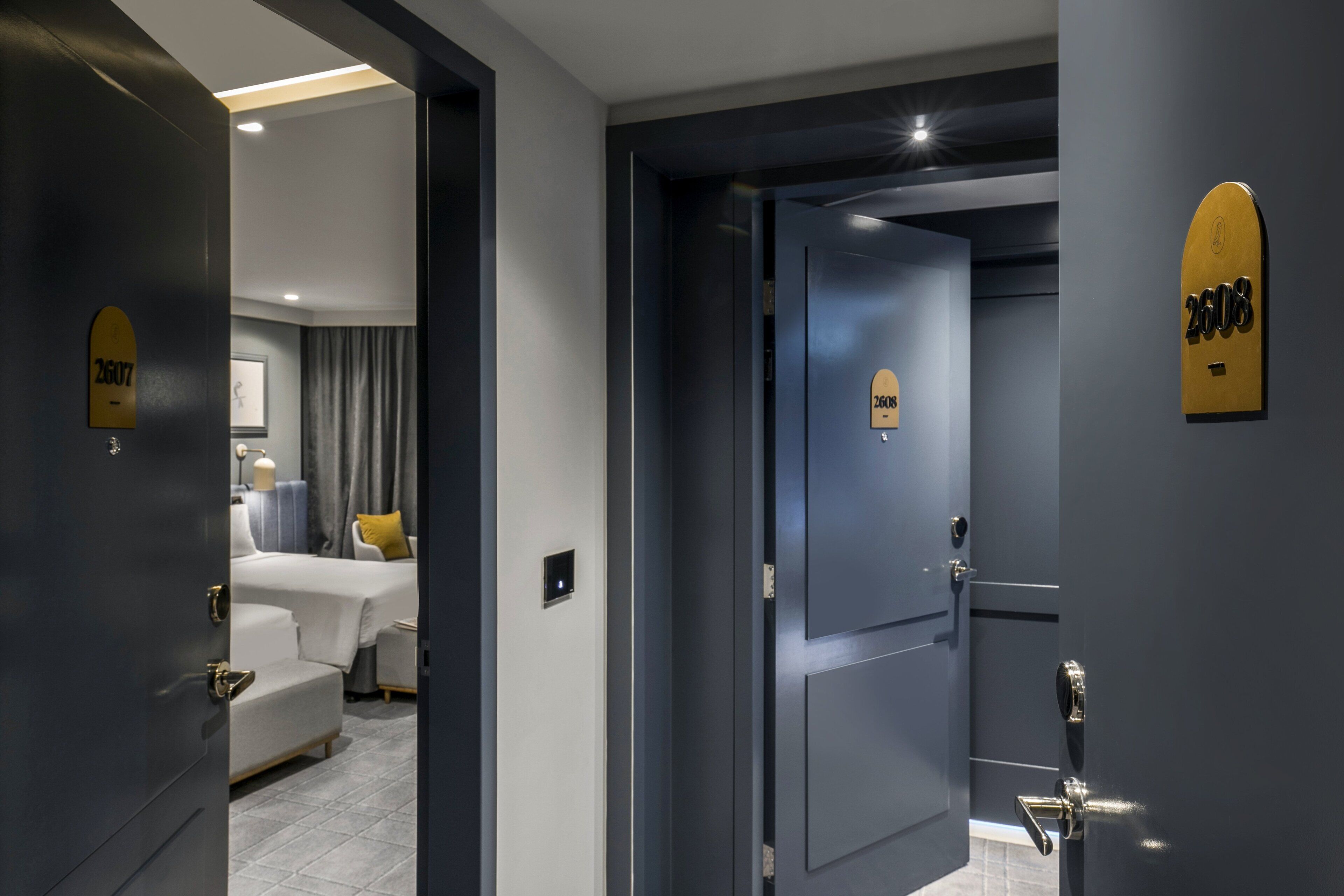 A hotel room with a bed, a bedside table, and a wall-mounted light fixture.