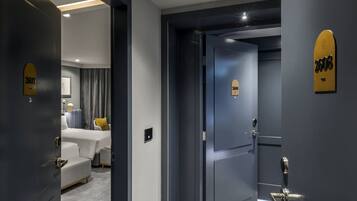 A hotel room with a bed, a bedside table, and a wall-mounted light fixture.