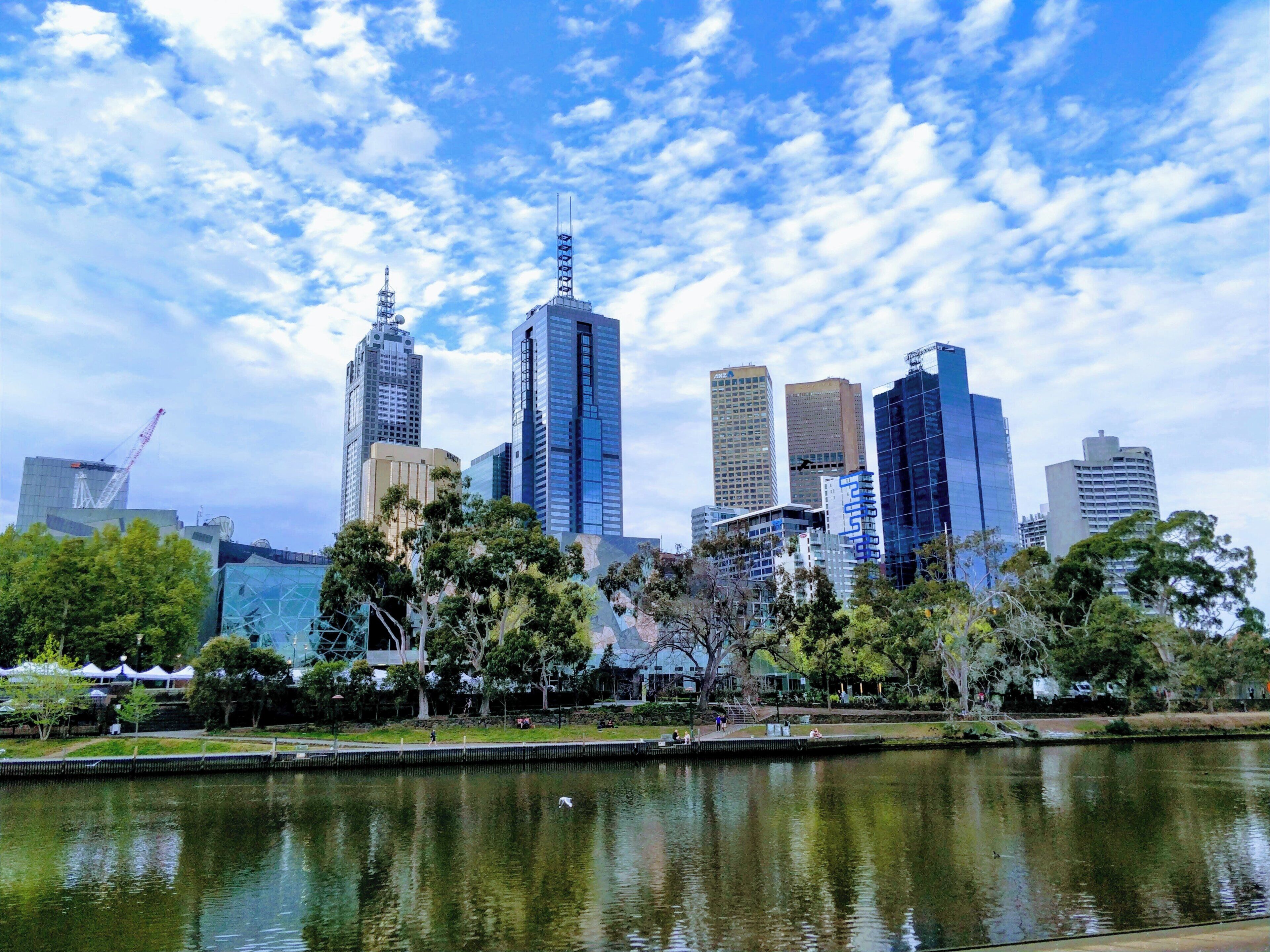 Un horizonte urbano con edificios modernos, una masa de agua y árboles.