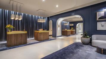 A modern reception area with two reception desks, a large mirror, and a seating area with a potted plant.