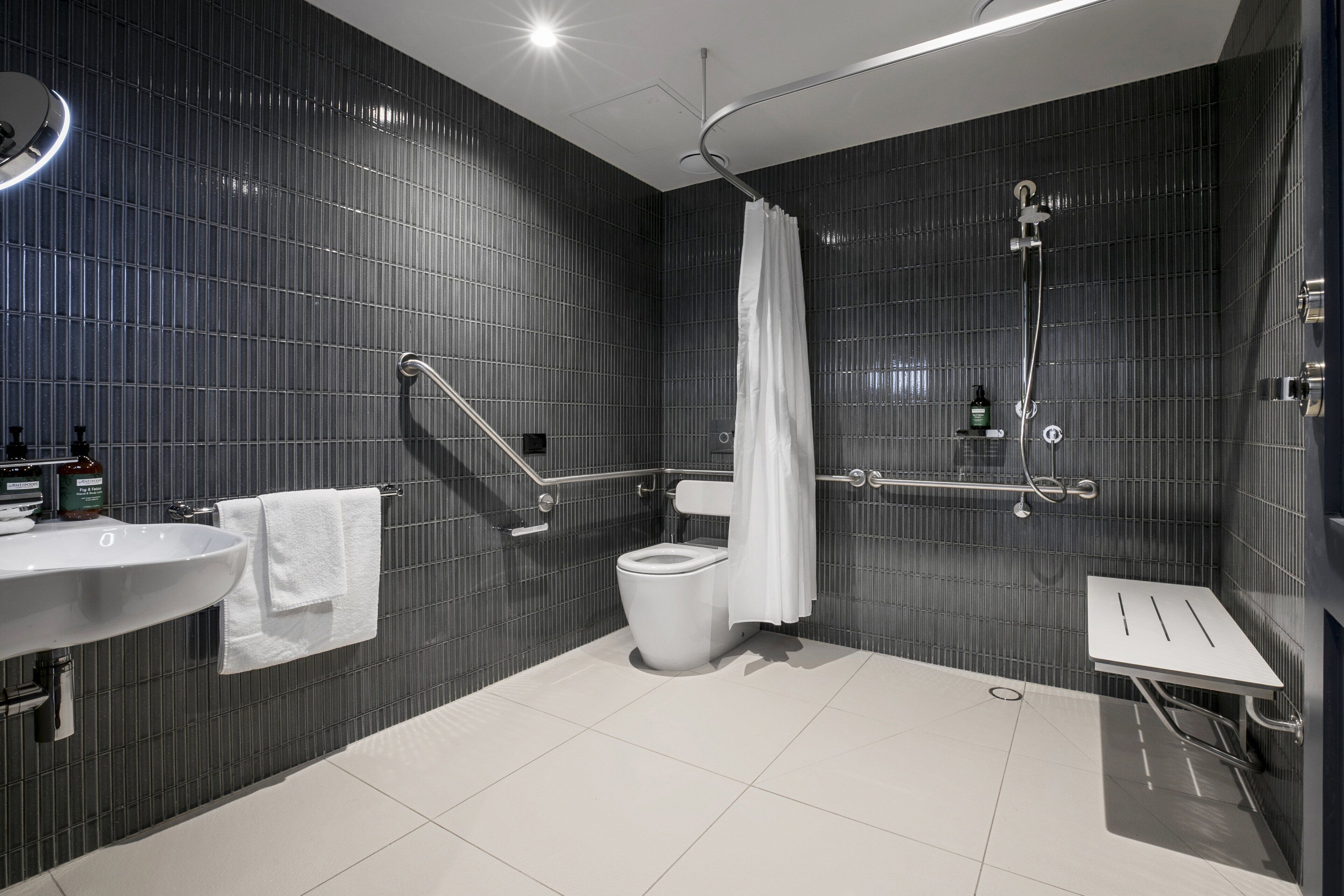 Un baño moderno con lavamanos, inodoro y zona de ducha blancos.
