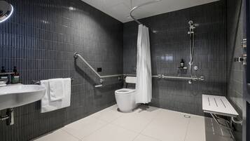 Un baño moderno con lavamanos, inodoro y zona de ducha blancos.