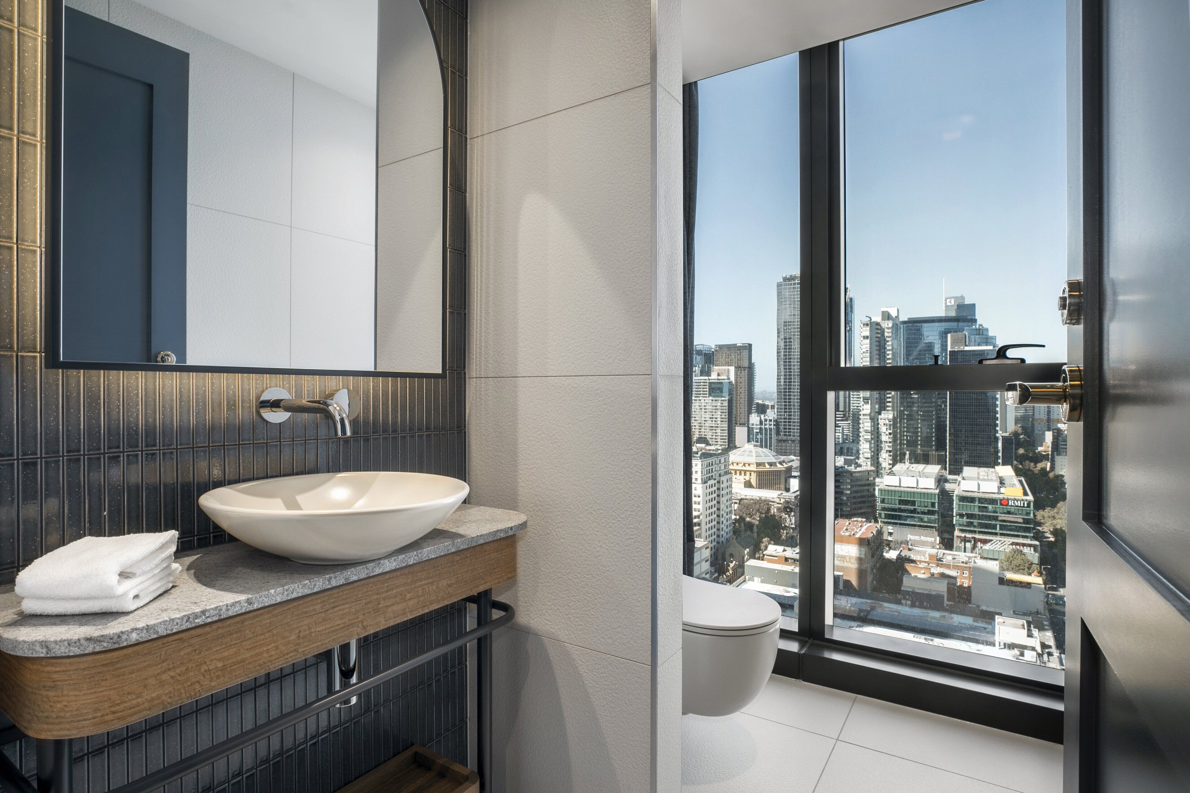 Un baño moderno con un ventanal grande, un lavamanos blanco y un espejo.