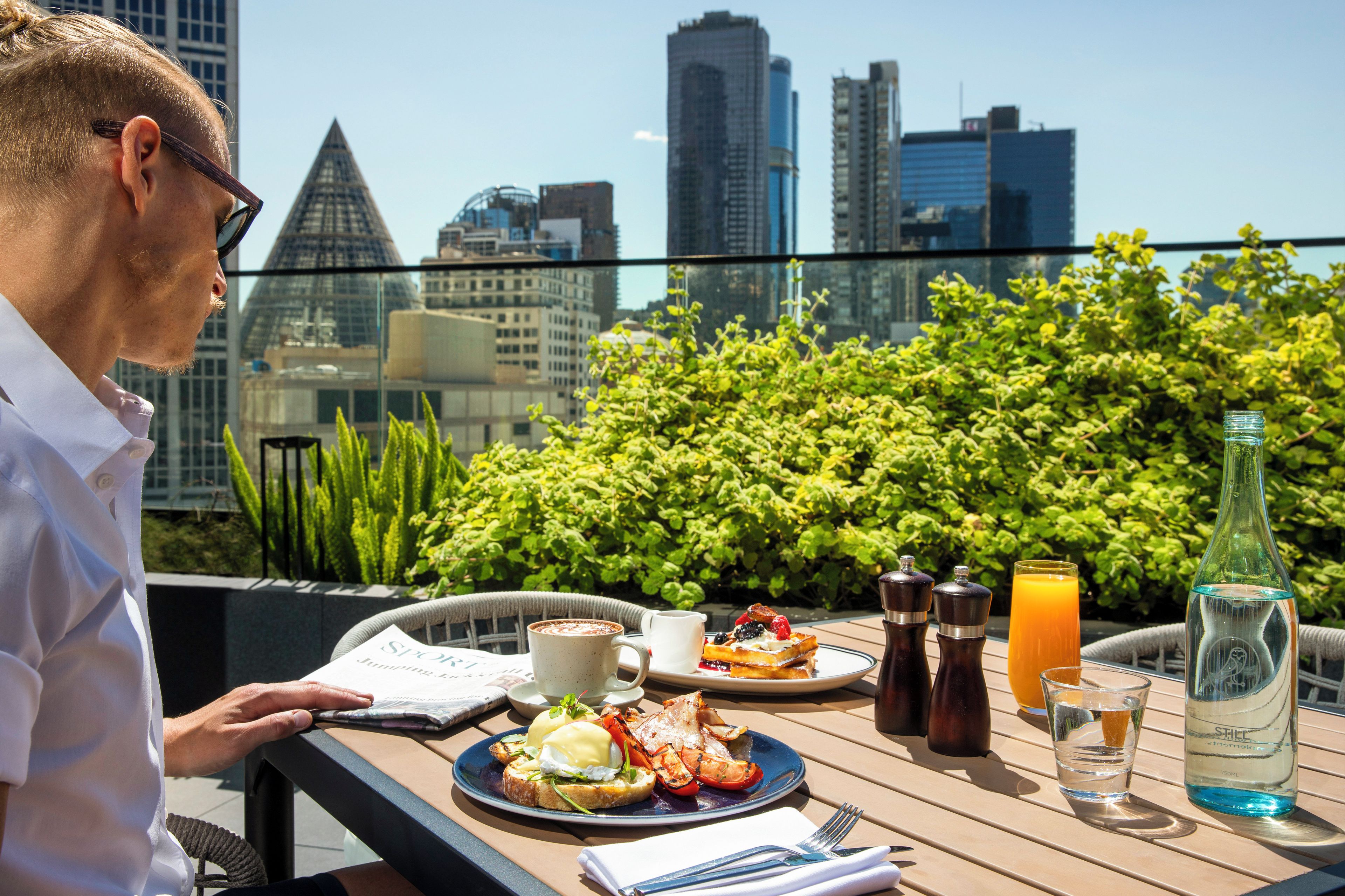 Una mesa de comedor con comida, bebidas y vistas a la ciudad.
