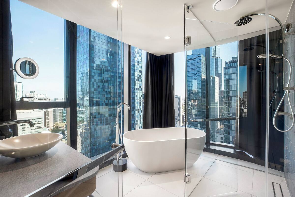 A modern bathroom with a freestanding bathtub, a large mirror, and a glass-enclosed shower.