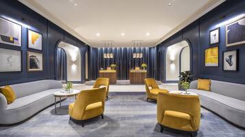 Een moderne zithoek met een bank, fauteuils, een salontafel en een receptiebalie.