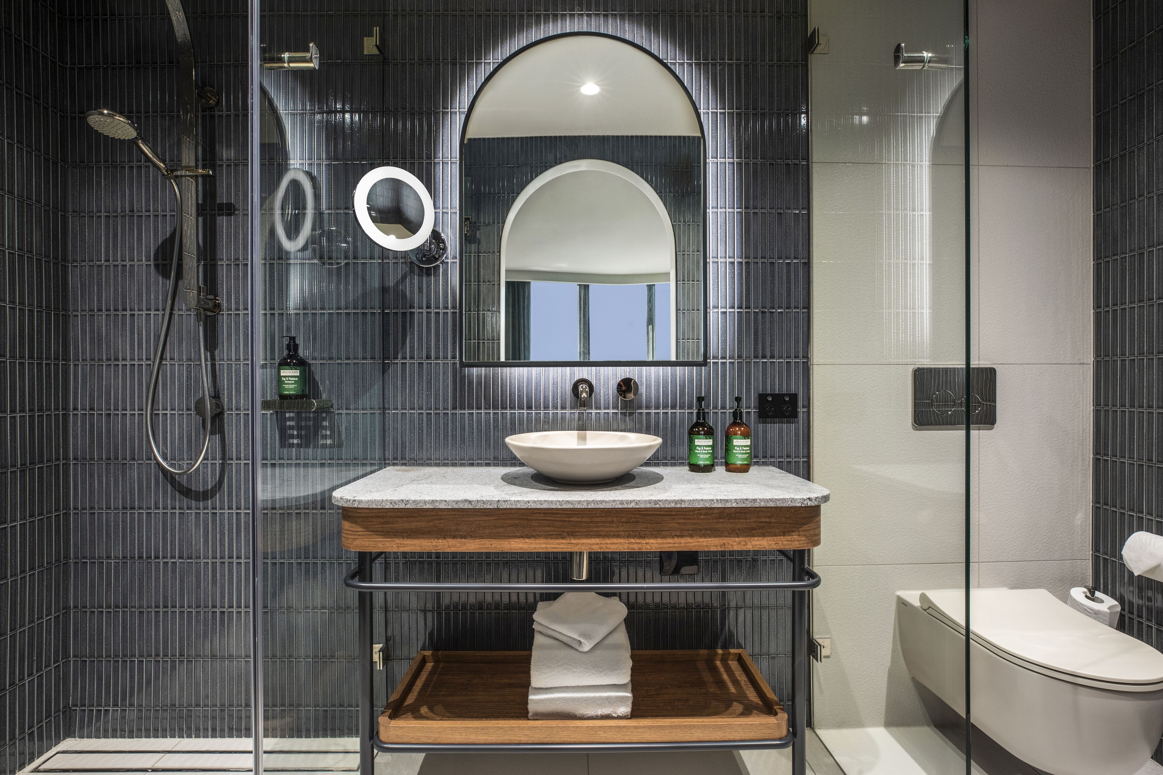 A modern bathroom with a glass-enclosed shower, a freestanding sink with a marble countertop, and a large mirror above the sink.