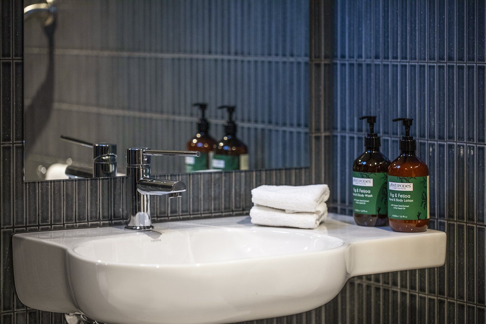 A bathroom sink with a mirror, a towel, and two bottles of body lotion.